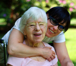 young girl hugging grandmother in wheelchair